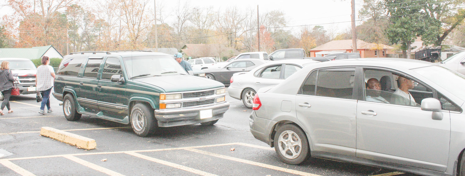 A double row of cars awaits the assignment of their pickup numbers Saturday morning during the annual Mineola Caring & Sharing Christmas food and present distribution at the First United Methodist Church Ministries Center.