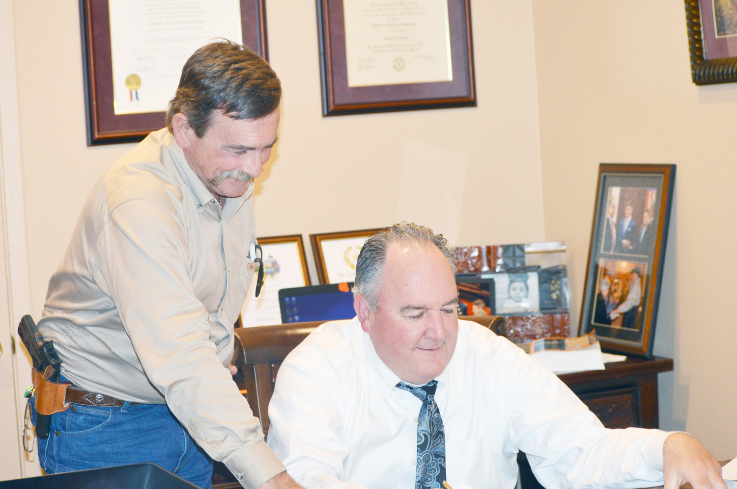 Wood County Sheriff Tom Castloo (standing) and 402nd District Court Judge Jeff Fletcher look over paperwork for upcoming trials in Wood County. (Monitor photo by Larry Tucker)