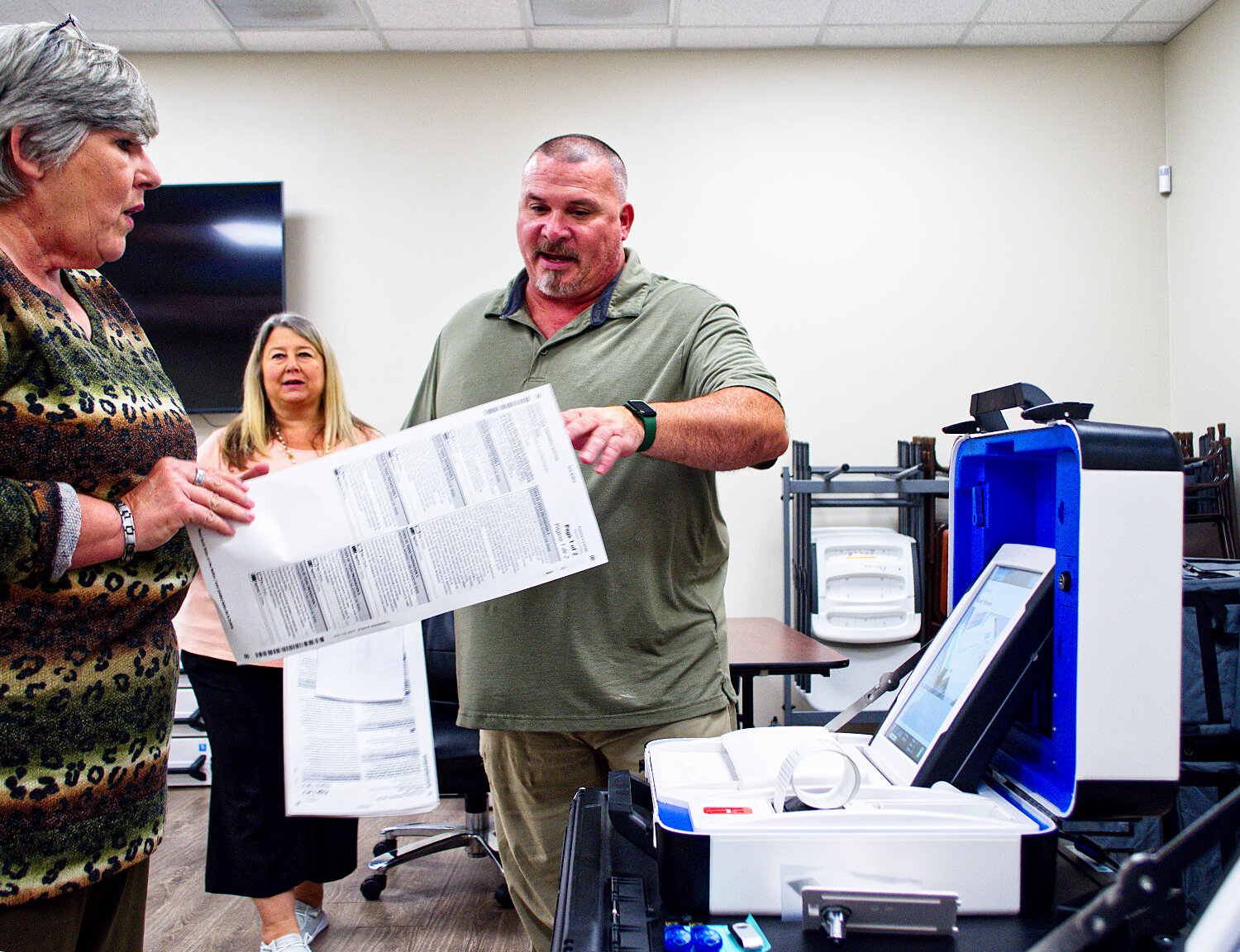 Jeremy Phillips with the Wood County elections office assists Tax Assessor Collector Carol Taylor with a test ballot as Elections Administrator Laura Wise observes.
