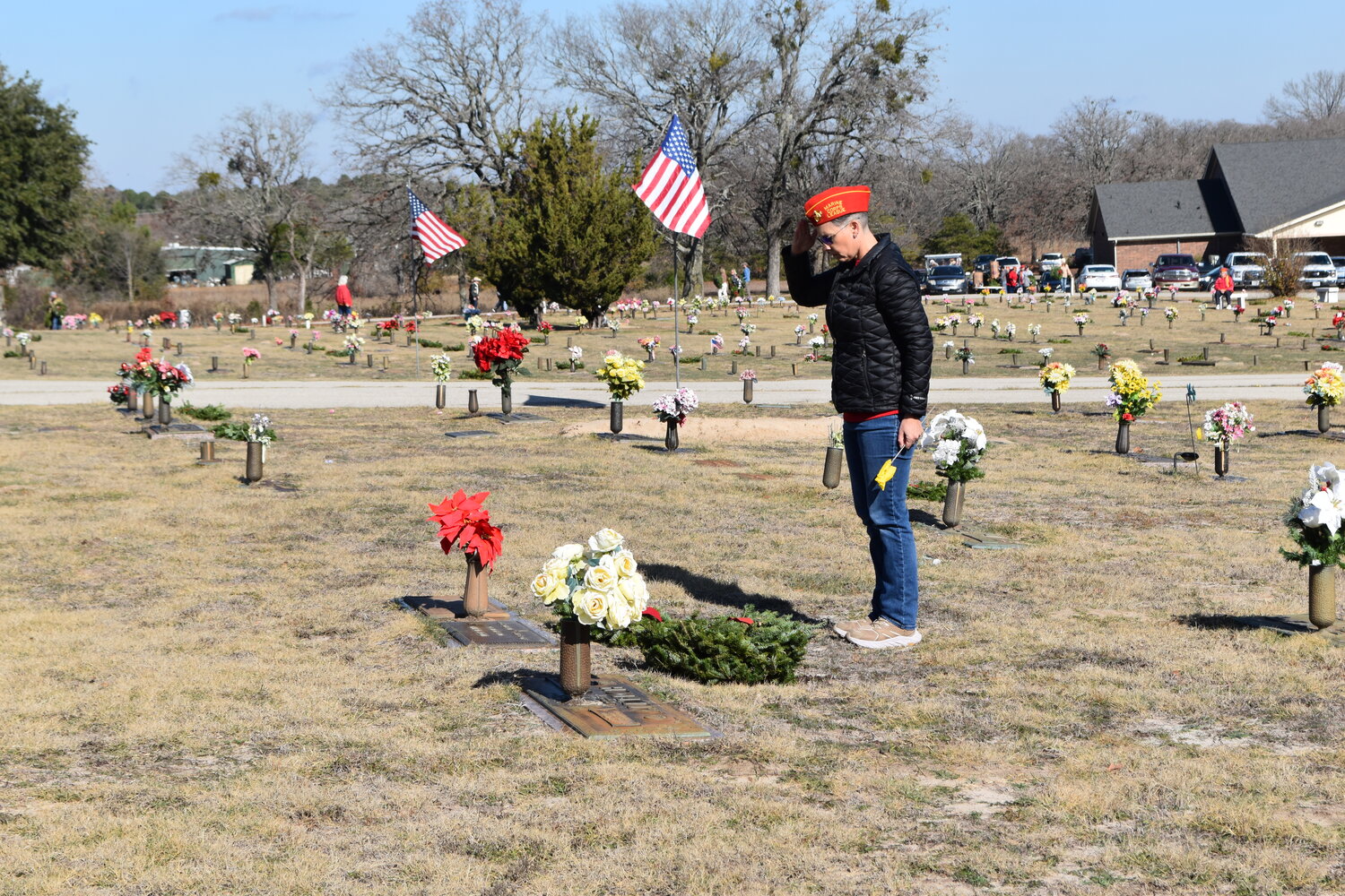 Jenni Biesheuvel with the Wood County Marine Corps League salutes after placing a wreath on a veteran’s grave at Roselawn Memorial Garden north of Mineola Saturday.