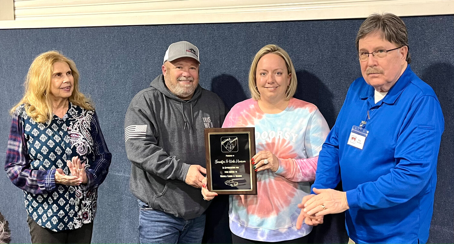 Jennifer and Kirk Hensen were honored for their service to Mineola Caring & Sharing at the recent annual meeting. The Hensens have organized a car show fundraiser for the last two years. The September show benefited C&S $12,000. Presenting the appreciation plaque were Joyce Curry, president and Roy Shockey, project chair.