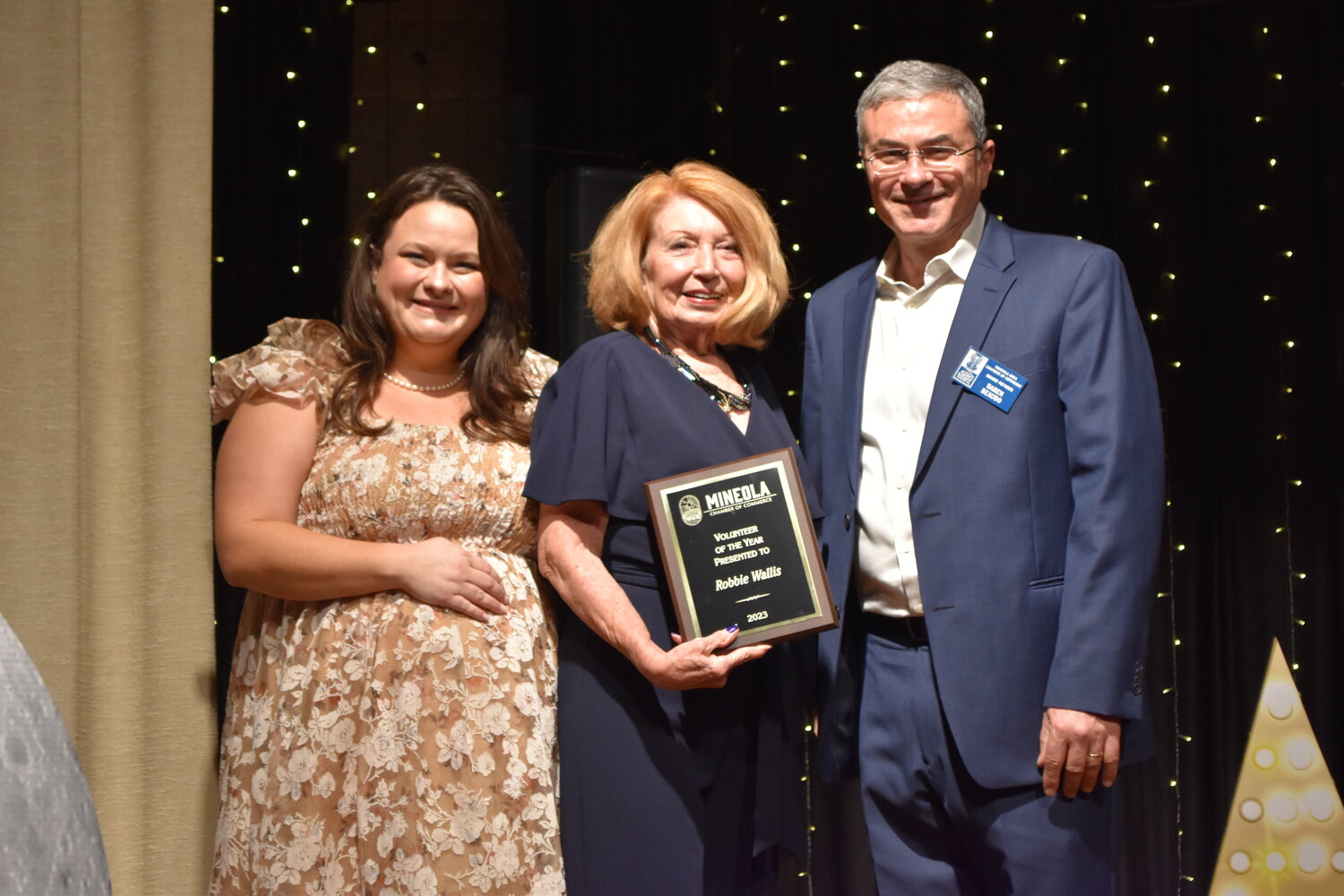 Mineola Chamber of Commerce Volunteer of the Year is Robbie Wallis, center, congratulated by President Kelsie McGilvray and Vice President Daren Beaudo at last week’s annual banquet.